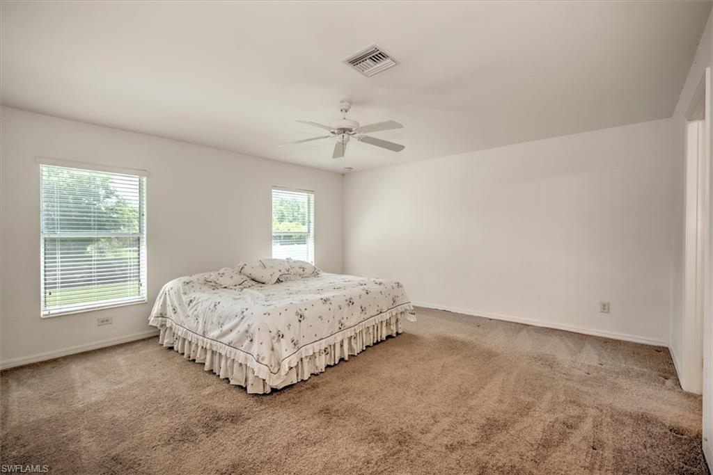 Carpeted main bedroom featuring ceiling fan