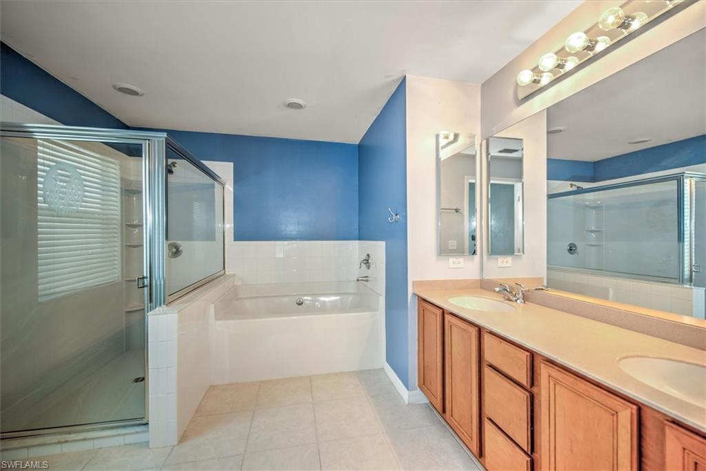 Bathroom featuring dual vanity, shower with separate bathtub, and tile floors