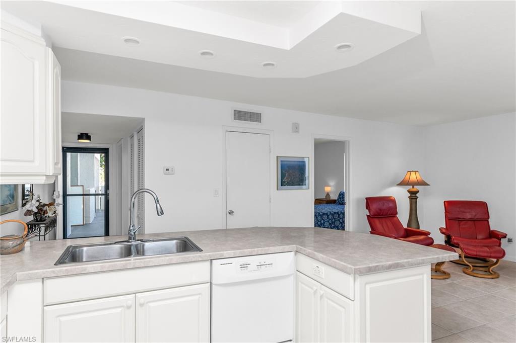 Kitchen with visible vents, dishwasher, a sink, light countertops, and white cabinetry