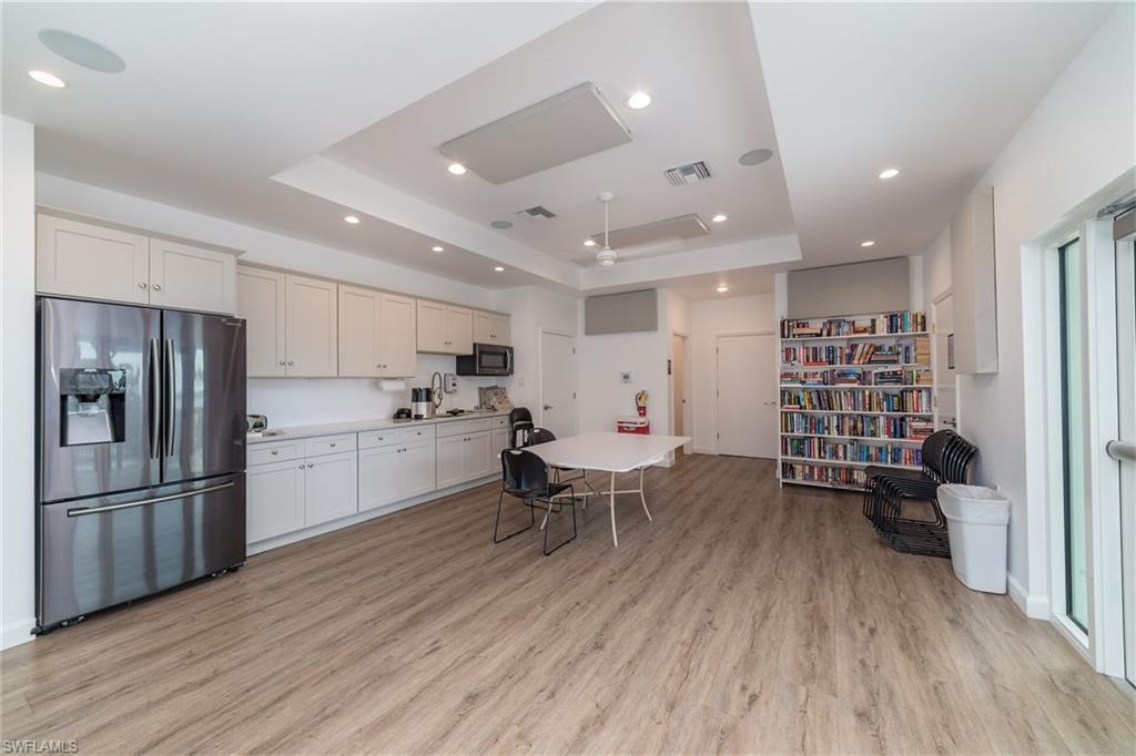 Kitchen with visible vents, stainless steel refrigerator with ice dispenser, light countertops, light wood-type flooring, and a tray ceiling