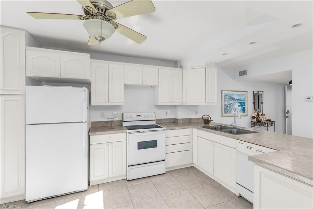 Kitchen with white cabinets, a sink, white appliances, and visible vents
