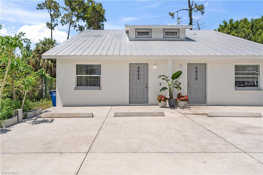 View of front of house with a patio area, metal roof, and stucco siding