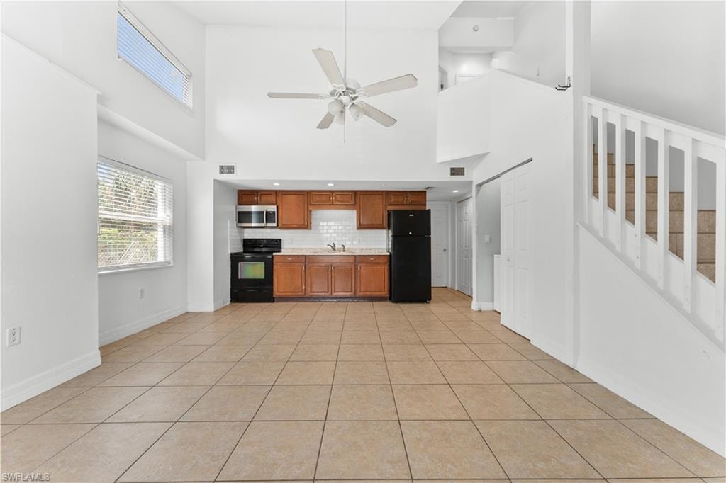 Kitchen featuring light countertops, black appliances, brown cabinets, decorative backsplash, and a sink