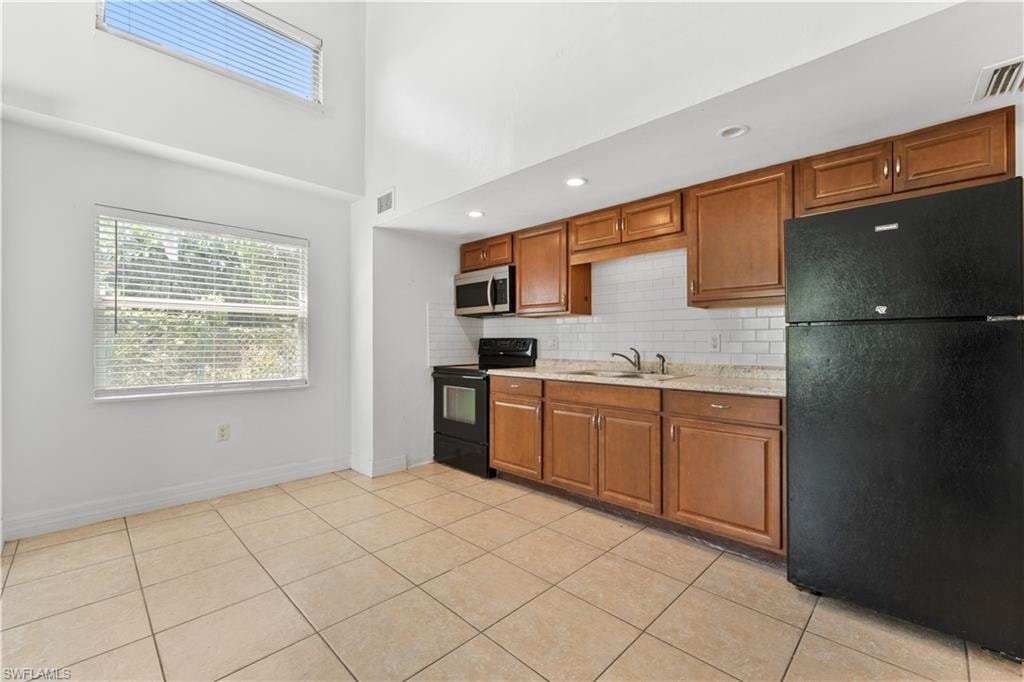 Kitchen with brown cabinetry, a sink, and black appliances