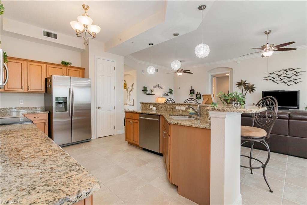 Kitchen featuring ceiling fan with notable chandelier, open floor plan, stainless steel appliances, and a sink