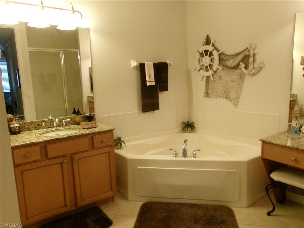 Full bath featuring a bath, tile patterned flooring, a shower stall, and vanity