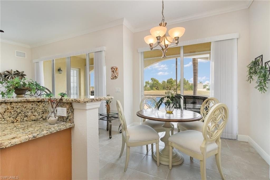 Dining area with light tile patterned flooring, baseboards, visible vents, a notable chandelier, and crown molding