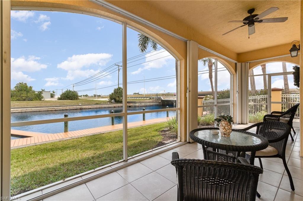 Sunroom / solarium featuring a water view, tile patterned floors, and a ceiling fan