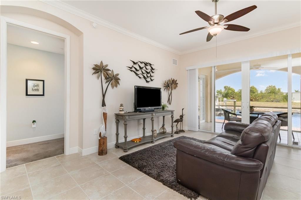 Living area with visible vents, a ceiling fan, light tile patterned floors, crown molding, and baseboards