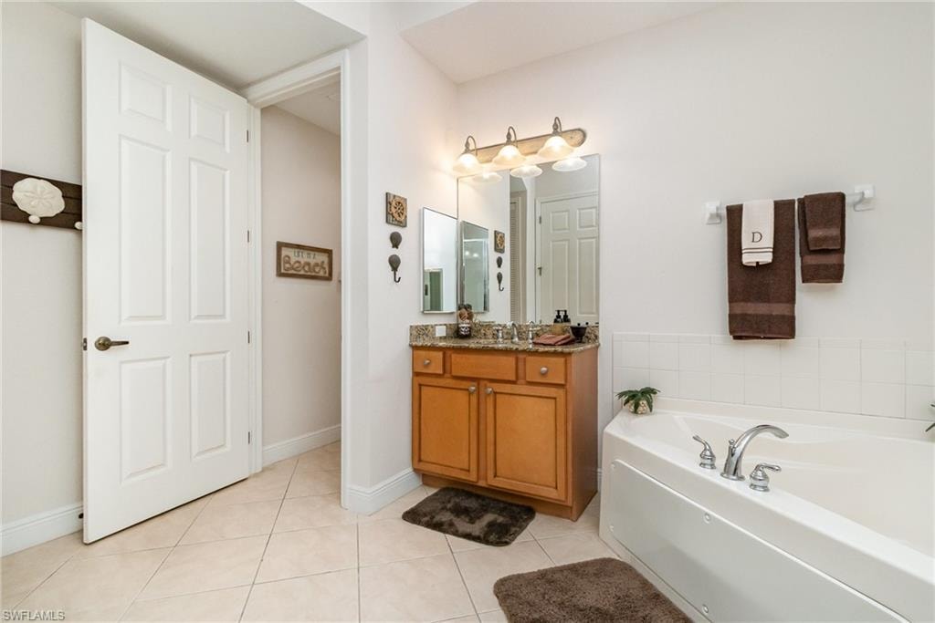 Full bathroom featuring a bath, tile patterned floors, baseboards, and vanity