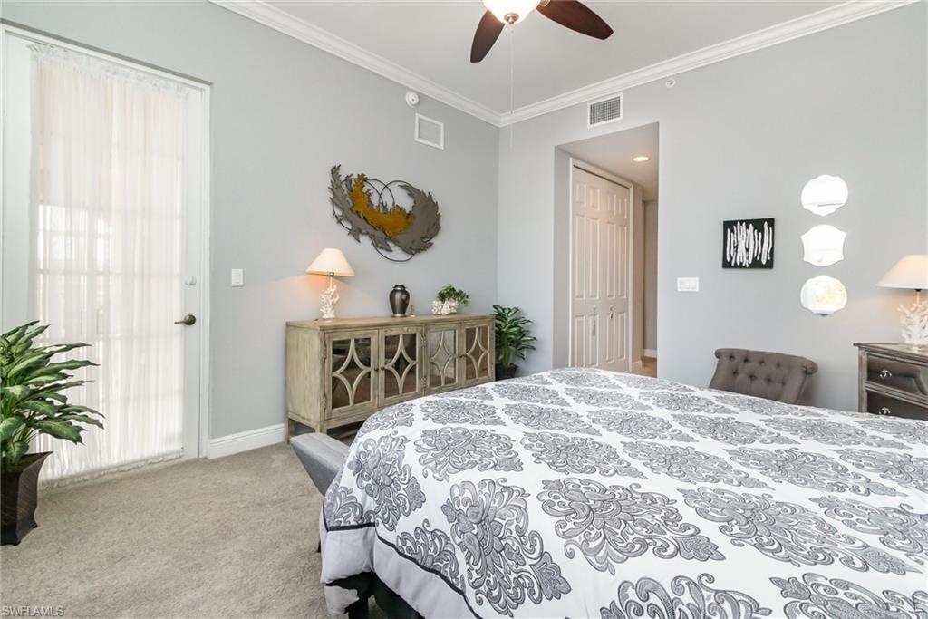 Carpeted bedroom with baseboards, a ceiling fan, visible vents, and crown molding