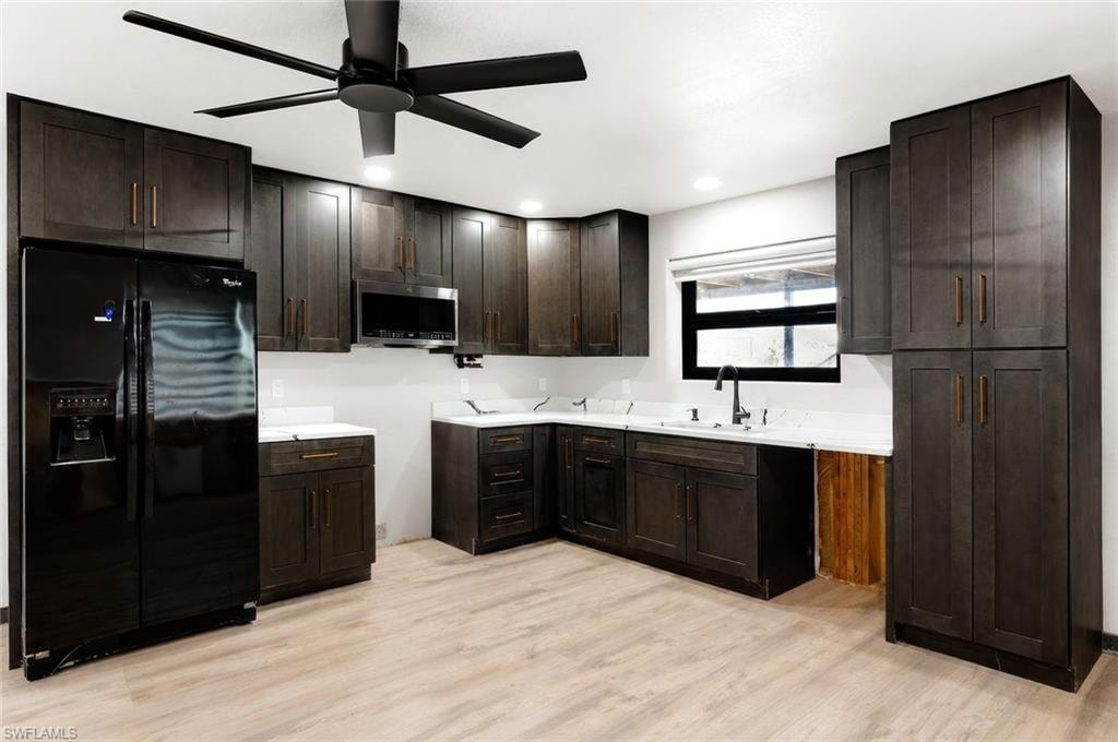 Contemporary kitchen featuring dark wood-finish cabinetry, bright white countertops, wood-finish flooring, and a ceiling fan with integrated lighting
