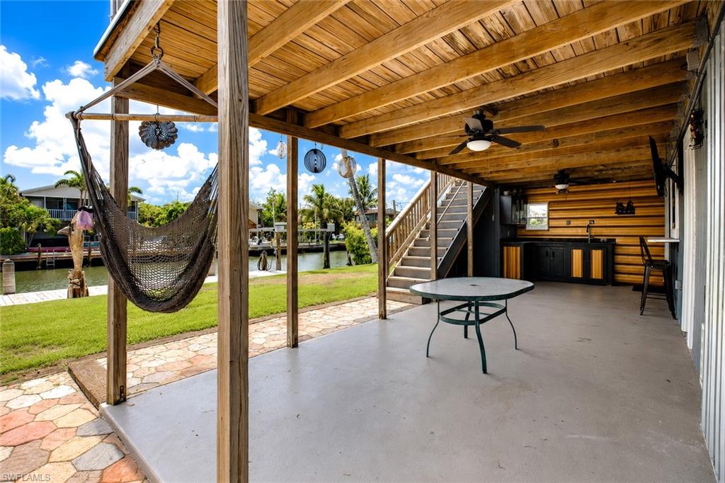 Covered patio featuring a built-in outdoor kitchen, ceiling fans, and wood beam ceiling