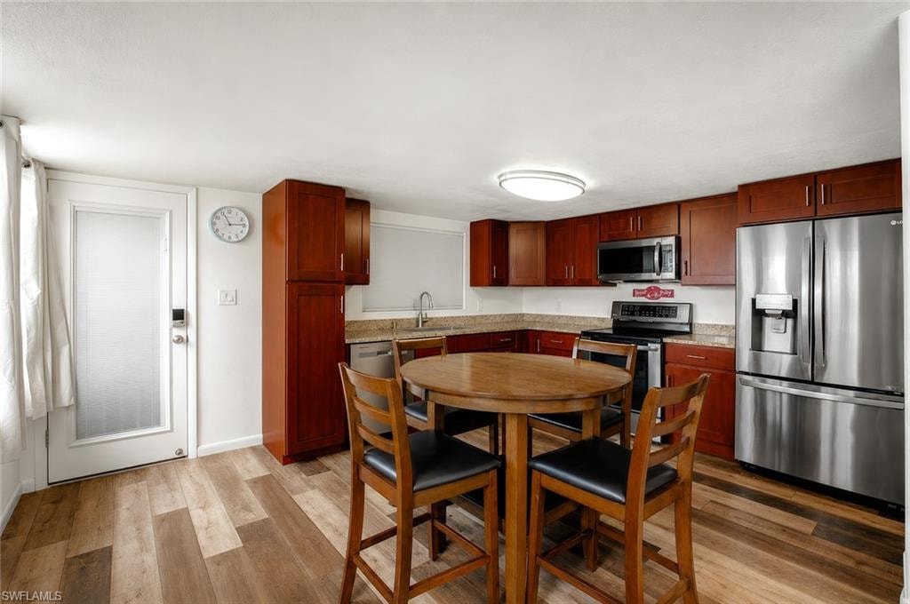 Kitchen featuring wood-finish flooring, dark wood cabinetry, stainless steel appliances, and solid surface countertops