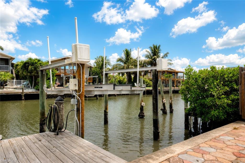 Waterfront property featuring a wood dock, boat lift system, and stone paver patio