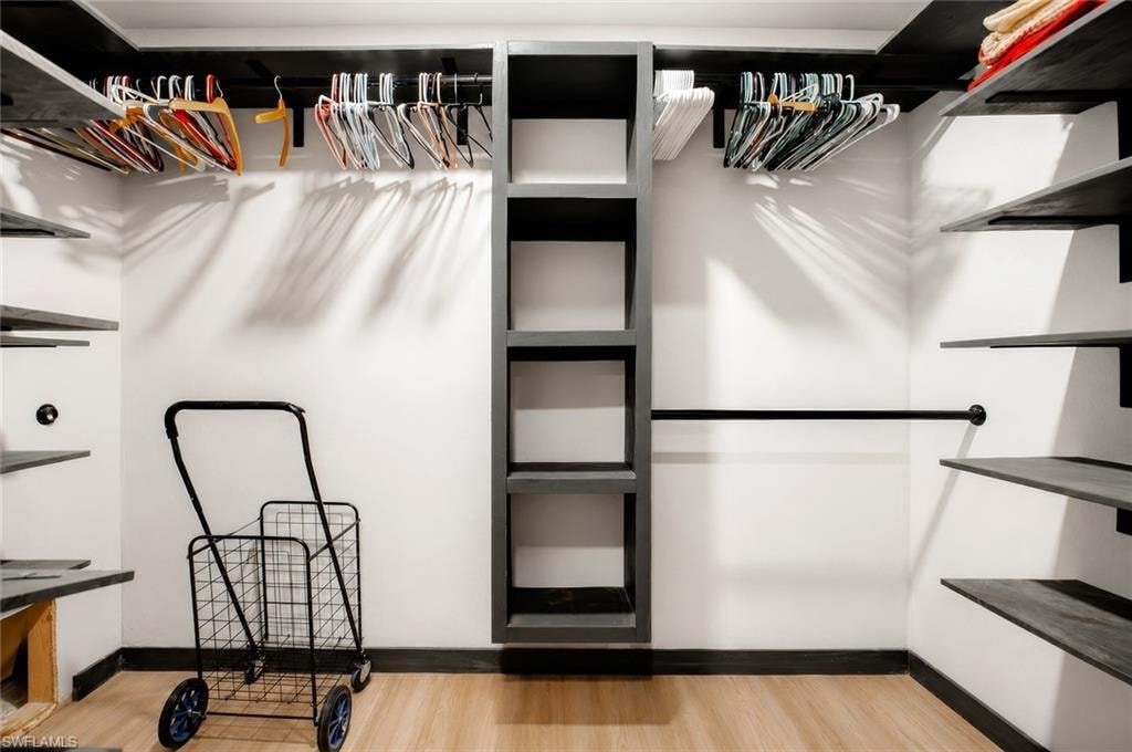 Custom closet system featuring built-in shelving, hanging rods, and wood-finish flooring