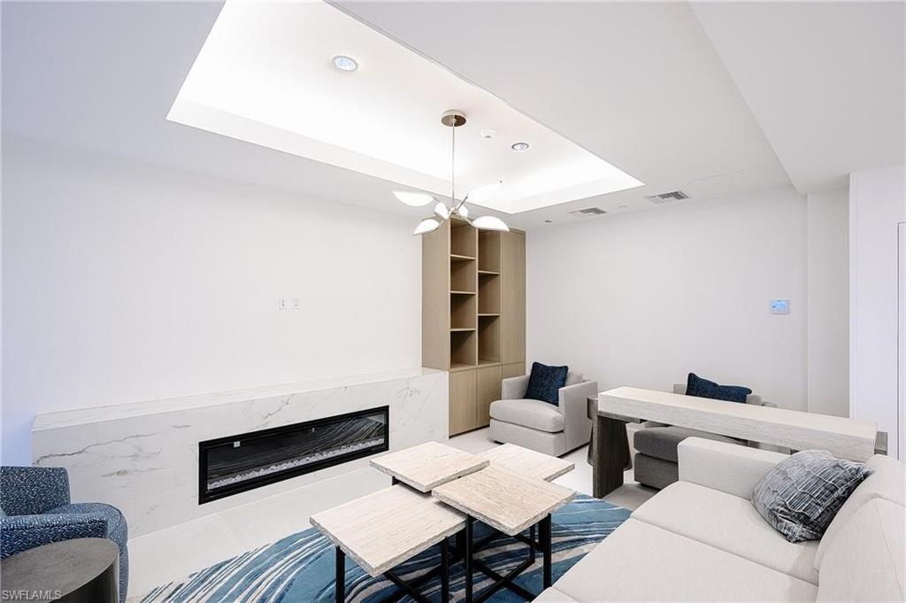 Living area with a tray ceiling, a fireplace, and recessed lighting