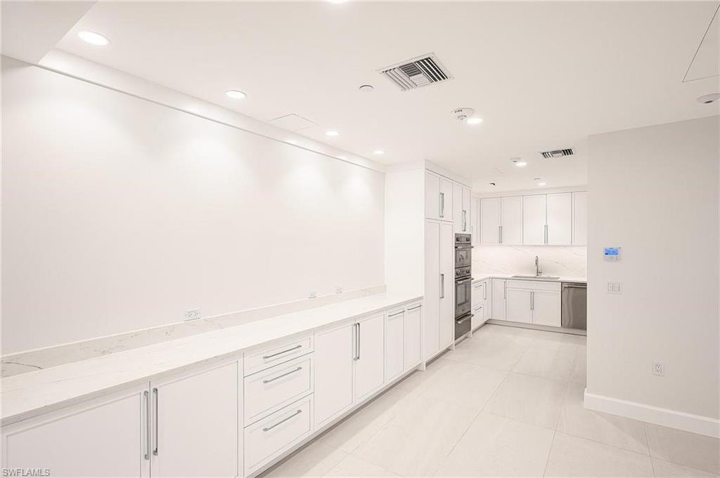 Kitchen featuring white cabinetry, light stone counters, recessed lighting, light tile patterned flooring, and stainless steel appliances