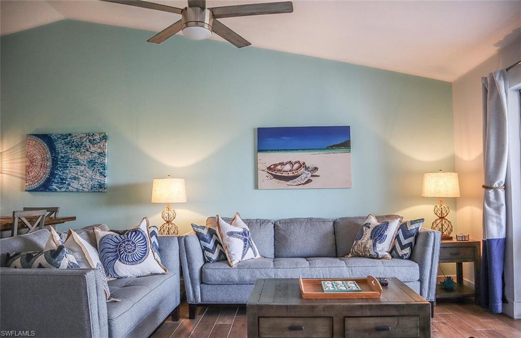 Living room featuring ceiling fan, dark wood-style floors, and vaulted ceiling