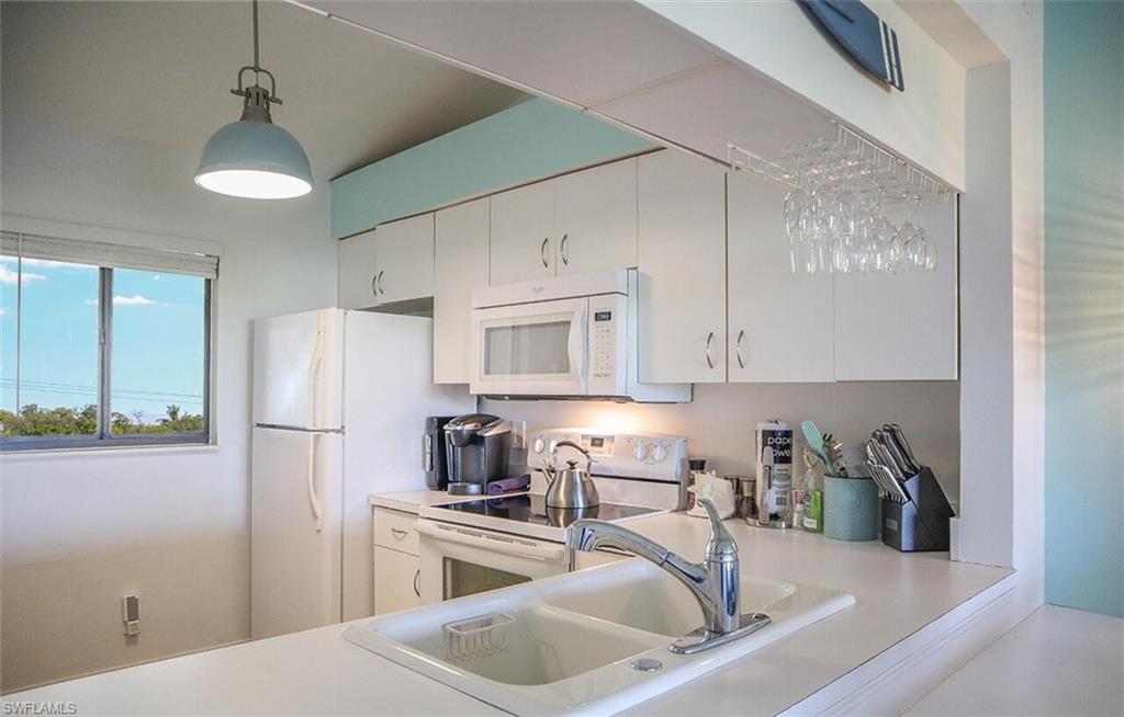 Kitchen featuring white appliances, light countertops, and white cabinets