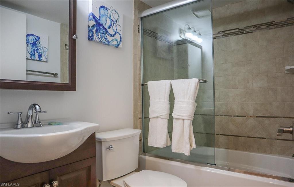 Bathroom with enclosed tub / shower combo, toilet, and vanity