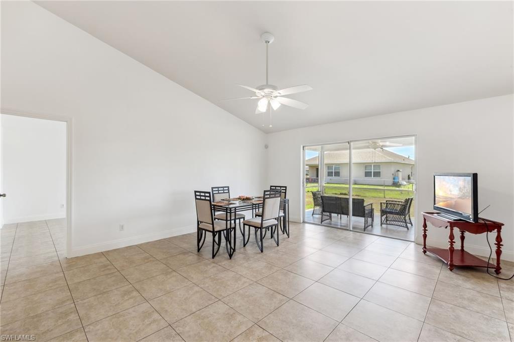Dining room featuring light tile patterned flooring, high vaulted ceiling, a ceiling fan, and baseboards
