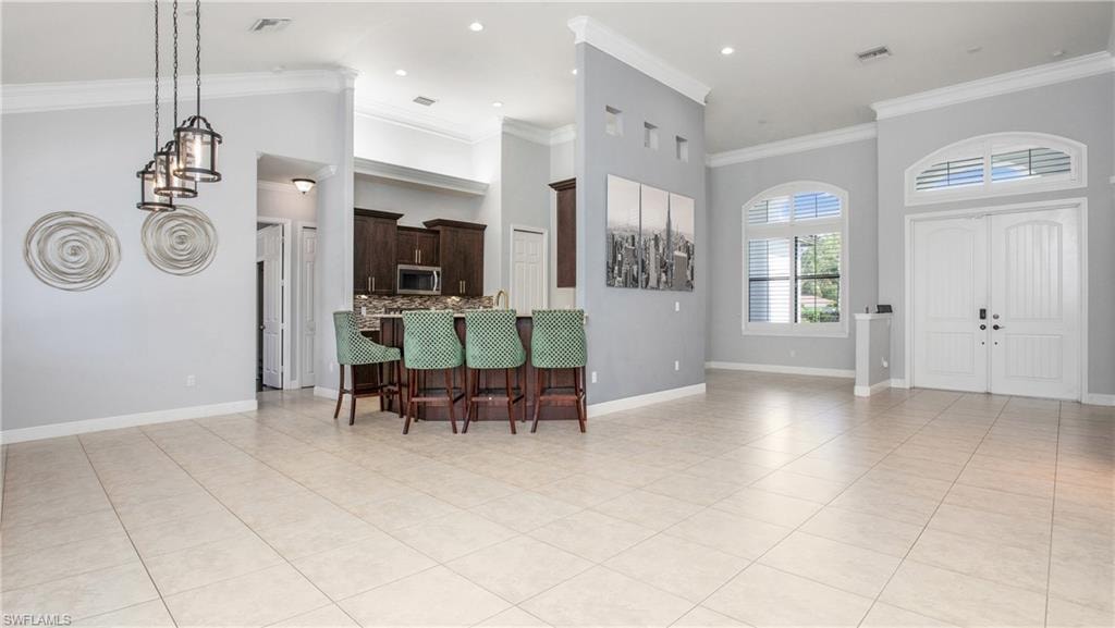 Entryway with light tile patterned floors, crown molding, baseboards, a high ceiling, and recessed lighting