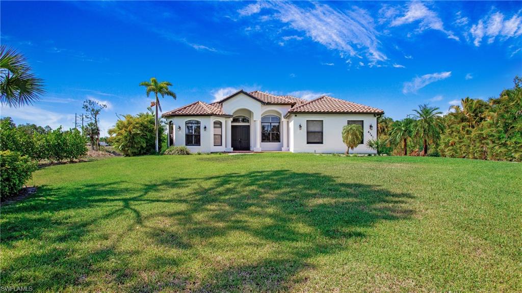 Mediterranean / spanish-style house with a front lawn, stucco siding, and a tile roof