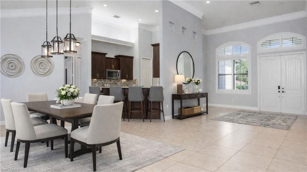 Virtually Staged  Dining room with a high ceiling, crown molding, and light tile patterned flooring