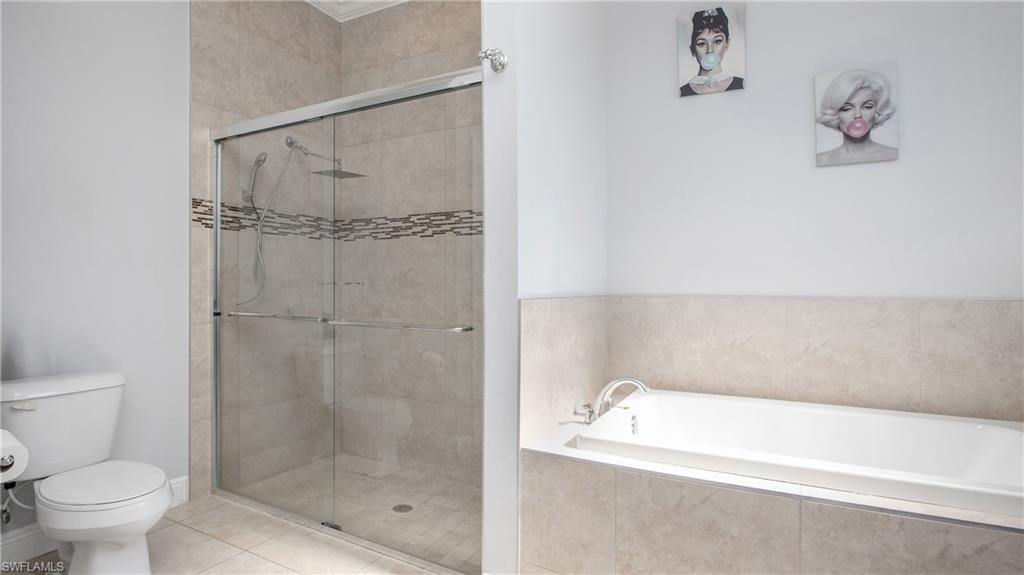 Bathroom with a stall shower, toilet, a bath, and tile patterned flooring