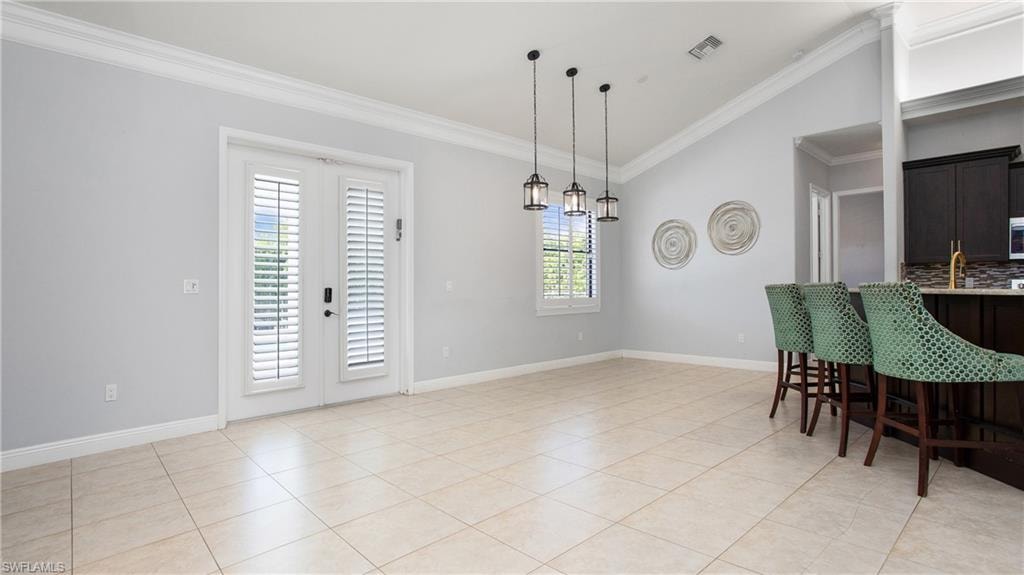 Dining room featuring crown molding, vaulted ceiling, light tile patterned floors, and baseboards