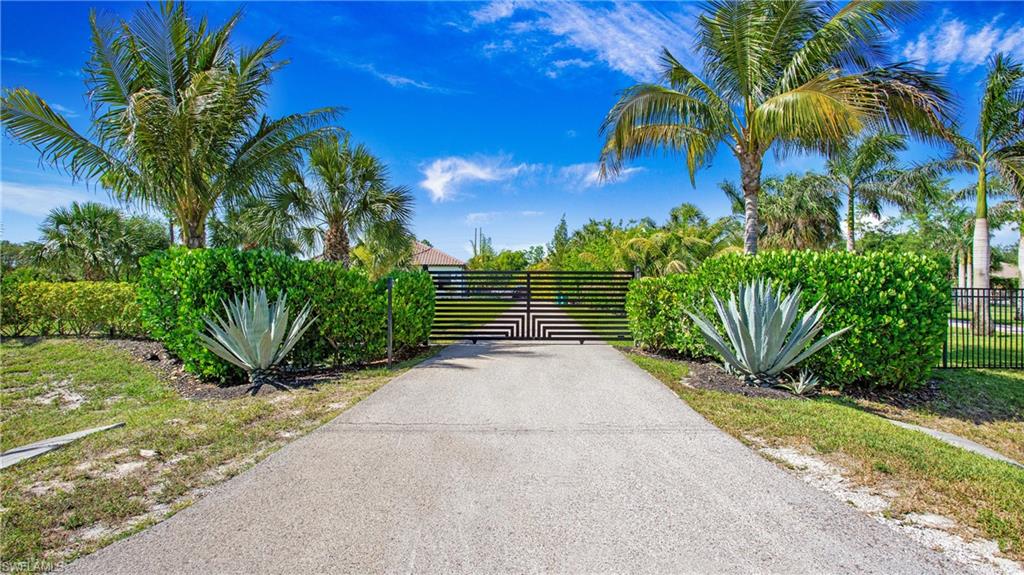 View of asphalt driveway with a gate and a gated entry