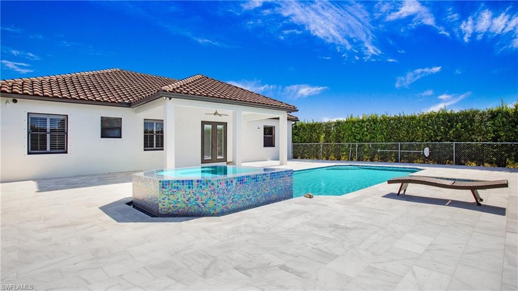 View of swimming pool with a patio, fence, a ceiling fan, french doors, and a pool with connected hot tub