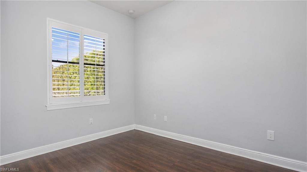 Spare room featuring baseboards and dark wood-style floors