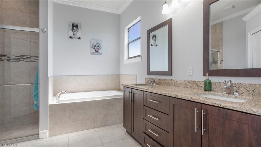Bathroom with a tile shower, crown molding, a garden tub, double vanity, and tile patterned floors