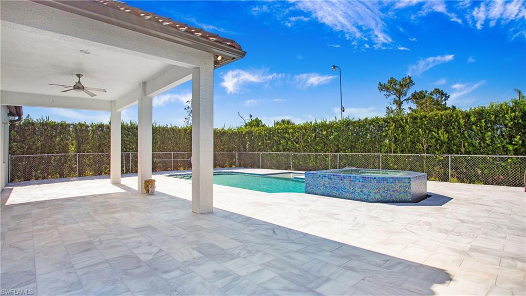 View of pool featuring ceiling fan, a patio, a fenced backyard, and a pool with connected hot tub
