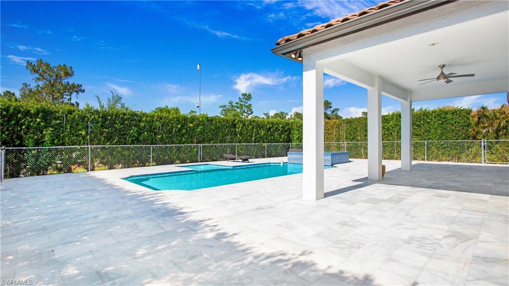 View of swimming pool with ceiling fan, fence, and a patio
