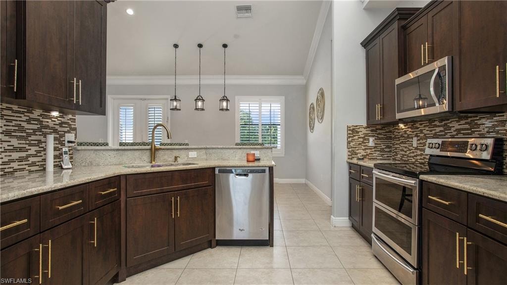 Kitchen with appliances with stainless steel finishes, crown molding, a sink, tasteful backsplash, and plenty of natural light