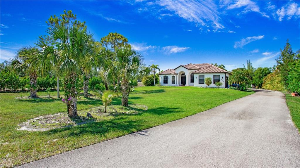 Mediterranean / spanish-style house with a front lawn, a tiled roof, stucco siding, and driveway