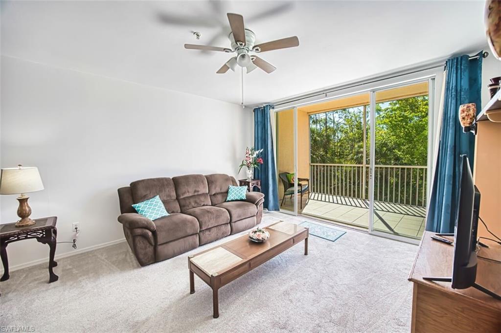 Carpeted living area featuring a ceiling fan and baseboards