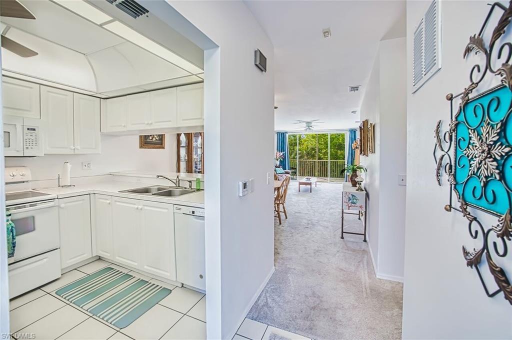 Kitchen featuring white cabinets, light countertops, a ceiling fan, a sink, and white appliances