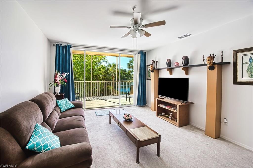 Living room featuring ceiling fan, carpet floors, a wall of windows, baseboards, and visible vents