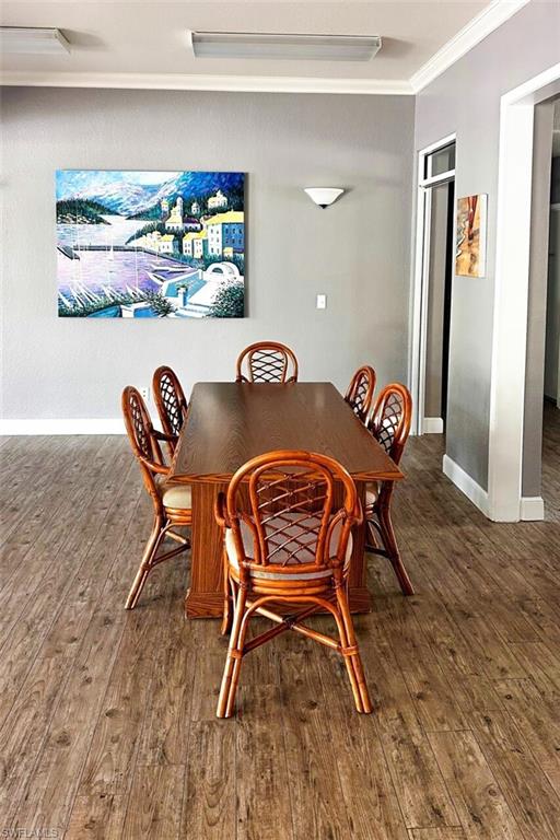 Dining space with wood finished floors, baseboards, and ornamental molding