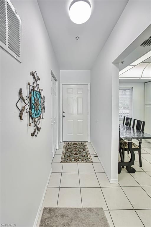 Doorway to outside featuring baseboards, visible vents, and light tile patterned flooring
