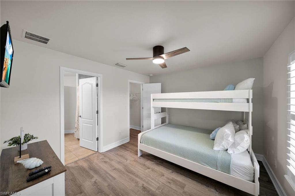Bedroom featuring visible vents, a ceiling fan, light wood finished floors, and baseboards