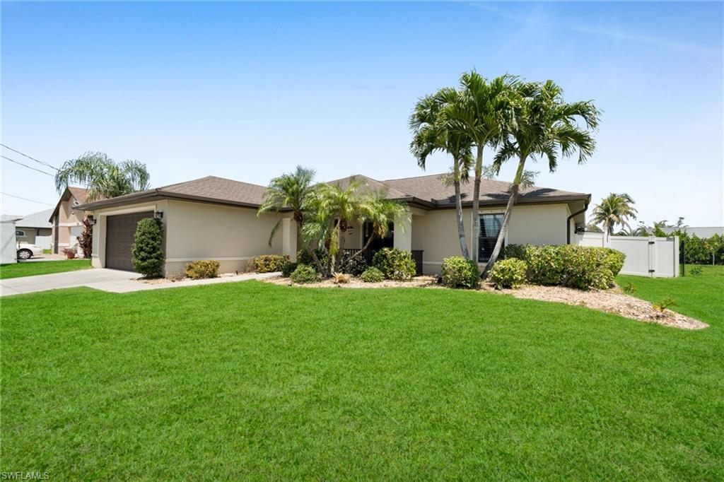 Ranch-style home featuring a front lawn, stucco siding, driveway, and an attached garage