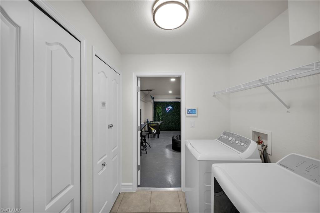 Clothes washing area with washing machine and dryer, laundry area, and baseboards