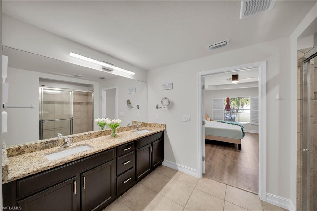 Full bathroom with visible vents, a stall shower, ensuite bath, and a sink