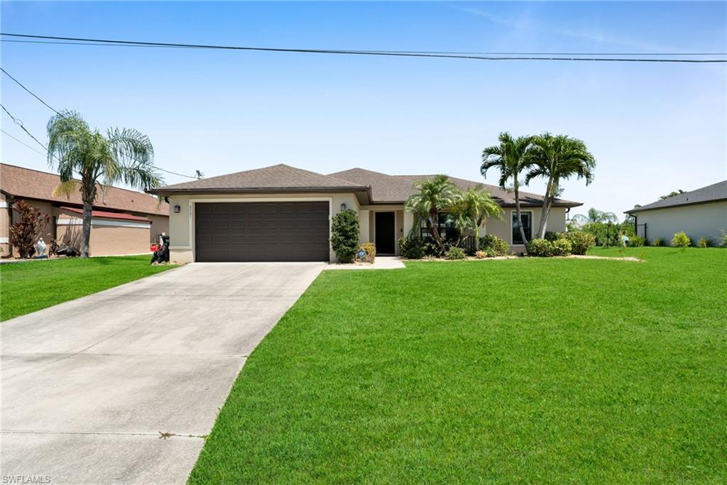 View of front of house with a garage, a front lawn, stucco siding, and driveway