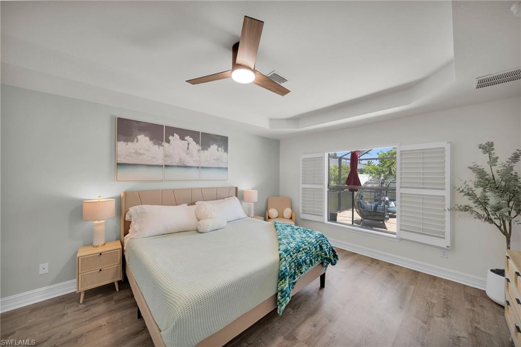 Bedroom featuring visible vents, a raised ceiling, and baseboards